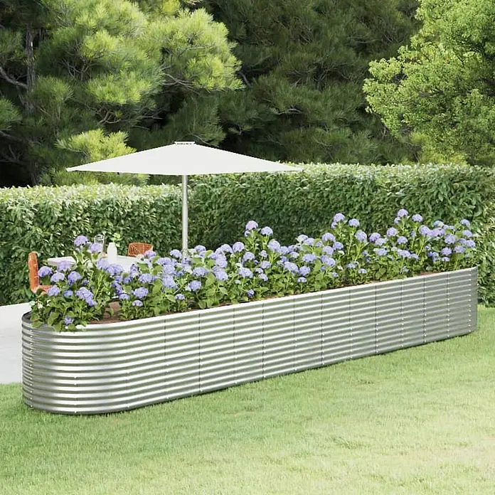 Furnicato Hochbeet - 554 x 100 x 68 cm, Stahl, Silber - Langes, gekrümmtes Hochbeet aus gewelltem verzinktem Stahl, gefüllt mit lila Blumen in einem Garten.