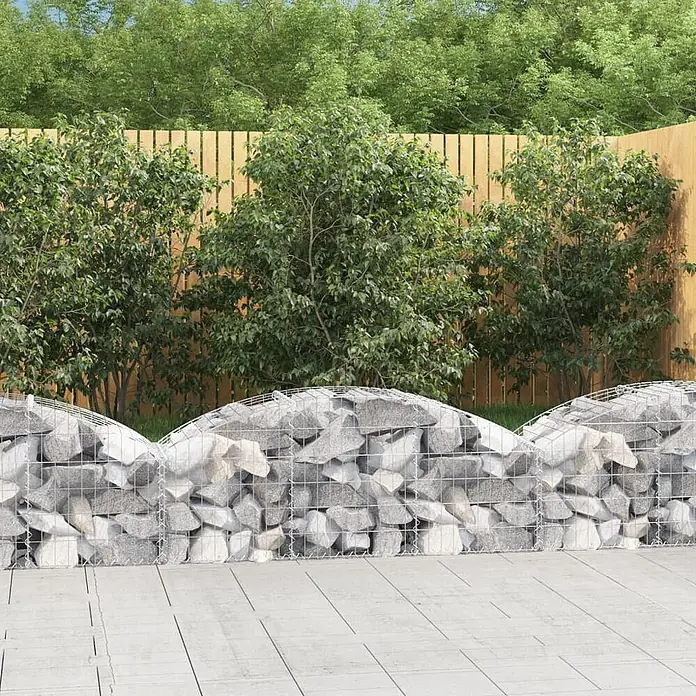 Furnicato Gabione - 60 x 150 x 50 cm, Metall, Maschenbreite: 50 mm, Maschenhöhe: 100 mm - Gabionenmauer mit hellgrauen Steinen und Drahtgeflecht, oben geschwungen, in einem Garten neben Terrasse und Holzzaun.