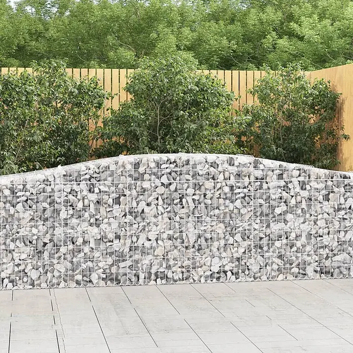 Furnicato Gabione - 50 x 400 x 100 cm, Metall, Maschenbreite: 50 mm, Maschenhöhe: 100 mm - Gabionenwand gefüllt mit hellgrauen Steinen in einer Gartenumgebung, mit Holzzaun und grüner Vegetation dahinter.