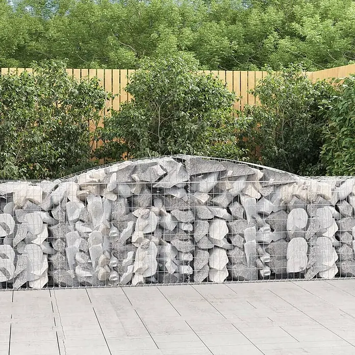 Furnicato Gabione - 100 x 400 x 50 cm, Metall, Maschenbreite: 50 mm, Maschenhöhe: 100 mm - Gabionenwand mit geschwungenem Oberteil, silbernem Gitter und grauen Steinen, im Garten.