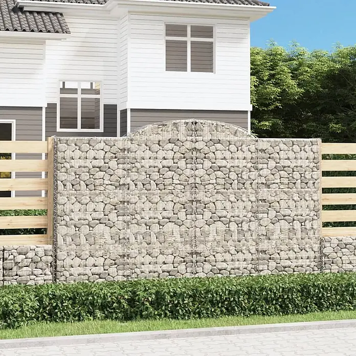 Furnicato Gabione - 200 x 300 x 50 cm, Metall, Maschenbreite: 50 mm, Maschenhöhe: 100 mm - Eine Gabionenwand aus hellgrauen Steinen mit integrierten Holzpaneelen als moderne Garteneinfriedung vor einem Haus.