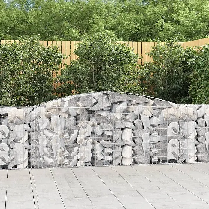 Furnicato Gabione - 100 x 400 x 30 cm, Metall, Maschenbreite: 50 mm, Maschenhöhe: 100 mm - Gabionenwand mit hellgrauen Steinen und geschwungener Oberseite, in einem Garten vor einem Holzzaun und Grün.
