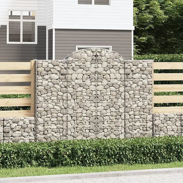 Furnicato Gabione - 180 x 200 x 50 cm, Metall, Maschenbreite: 50 mm, Maschenhöhe: 100 mm - Gabionen- und Holzzaun mit hellen Steinen, grenzt an ein Haus mit Hecken.