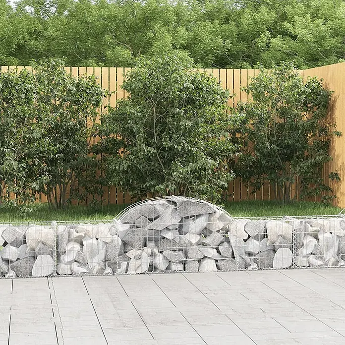 Furnicato Gabione - 30 x 200 x 60 cm, Metall, Maschenbreite: 50 mm, Maschenhöhe: 100 mm - Eine Gabionenwand aus Metallgitter, mit grauen Steinen gefüllt, dient als Gartenbegrenzung.