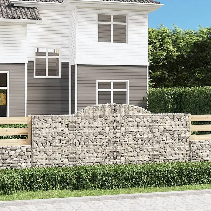 Furnicato Gabione - 140 x 300 x 30 cm, Metall, Maschenbreite: 50 mm, Maschenhöhe: 100 mm - Gabionenzaun mit steingefüllten Drahtkörben und horizontalen Holzbrettern als Garteneinfassung vor einem Haus.
