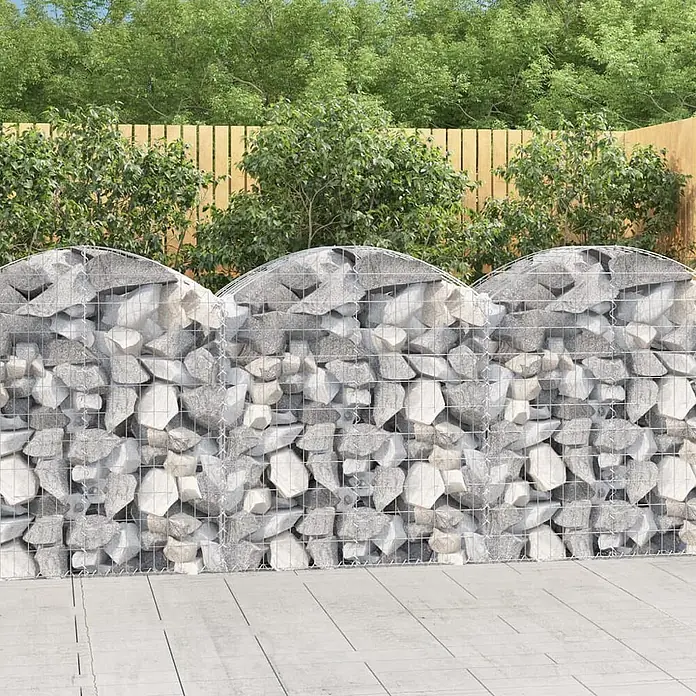 Furnicato Gabione - 50 x 100 x 120 cm, Metall, Maschenbreite: 50 mm, Maschenhöhe: 100 mm - Gabionenwand mit drei gewölbten Abschnitten aus Metallgeflecht und hellgrauen Steinen als Gartenabtrennung auf einer Terrasse.
