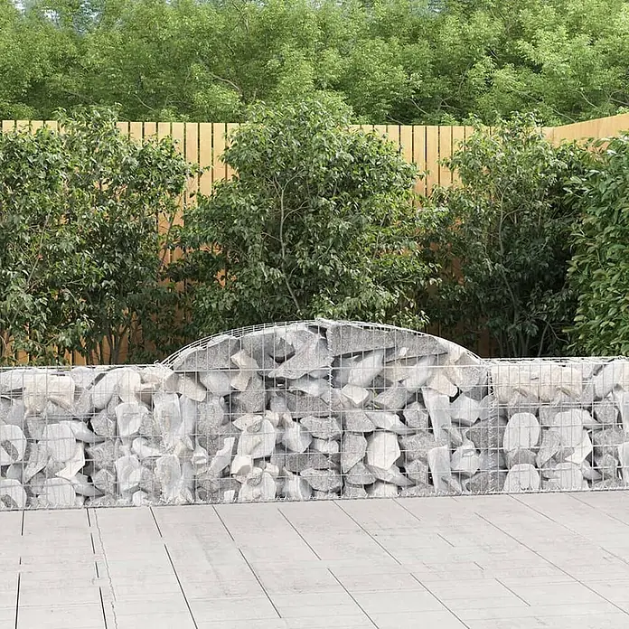 Furnicato Gabione - 30 x 300 x 80 cm, Metall, Maschenbreite: 50 mm, Maschenhöhe: 100 mm - Helle graue Steingabionenwand mit gewölbter Oberseite, trennt Terrasse und Garten mit Holzzaun.