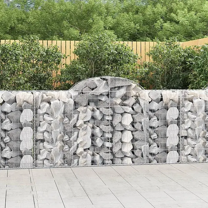 Furnicato Gabione - 50 x 200 x 120 cm, Metall, Maschenbreite: 50 mm, Maschenhöhe: 100 mm - Gabionenwand aus Drahtgeflecht und hellgrauen Steinen mit einem geschwungenen Oberteil im Garten.