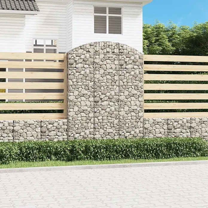 Furnicato Gabione - 30 x 150 x 220 cm, Metall, Maschenbreite: 50 mm, Maschenhöhe: 100 mm - Moderne Gabionenwand aus hellen Steinen mit hellem Holzlattenzaun, als Grundstücksbegrenzung vor einem Haus mit grünen Büschen.