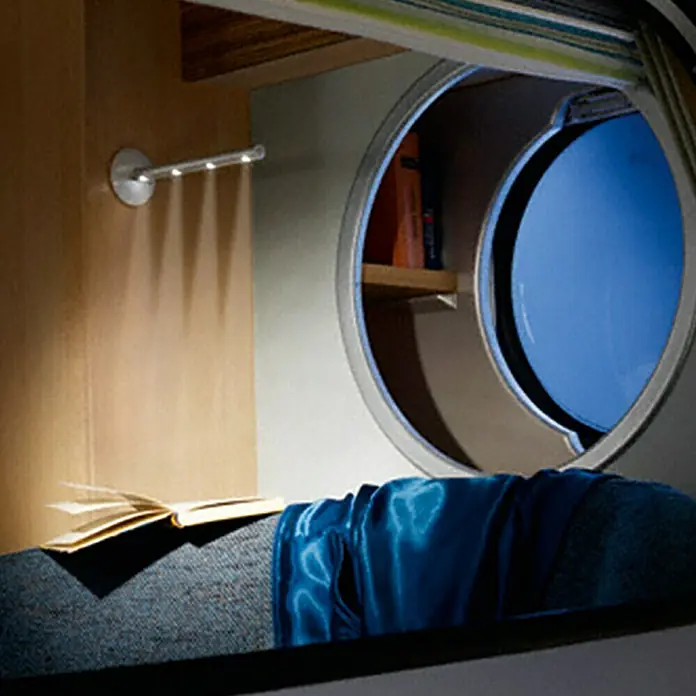 Osram LED-Leuchtstab LEDstixx - Silber, 1 Stk. - Nahaufnahme einer Leseecke mit einer runden Fensteröffnung, einem Buch und einer blauen Decke für eine gemütliche Atmosphäre.