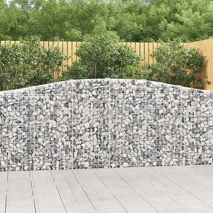 Furnicato Gabione - 30 x 400 x 120 cm, Metall, Maschenbreite: 50 mm, Maschenhöhe: 100 mm - Gabionenwand mit hellgrauen Steinen, leicht gewölbter Oberseite, in einem Gartenambiente.