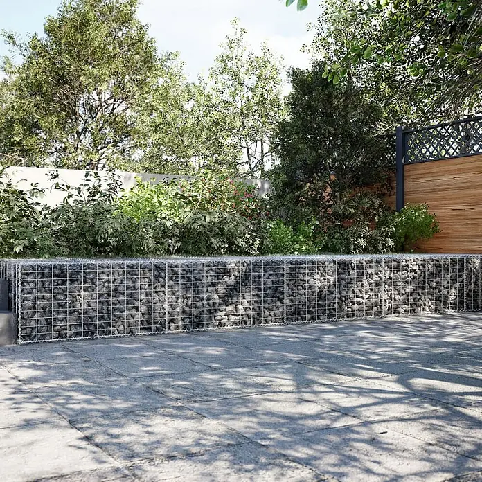 Furnicato Gabione - 900 x 100 x 50 cm, Metall, Maschenbreite: 50 mm, Maschenhöhe: 100 mm - Gabionenwand aus Drahtgeflecht, gefüllt mit dunkelgrauen Steinen, als Begrenzung in einem gepflasterten Garten.