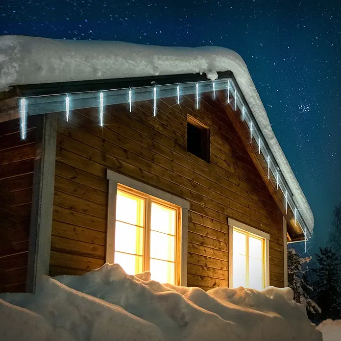 ECD Germany LED-Lichterkette 72 LEDs 6,9m für Innen & Außen IP44 Kaltweiß - Außen, Lichtfarbe: Kaltweiß, Anzahl Leuchtmittel: 72 Stk., Netzbetrieben - Klare Eiszapfenlichter leuchten an der Traufe eines gemütlichen Holzhauses, eingebettet in tiefen Schnee unter einem Sternenhimmel.