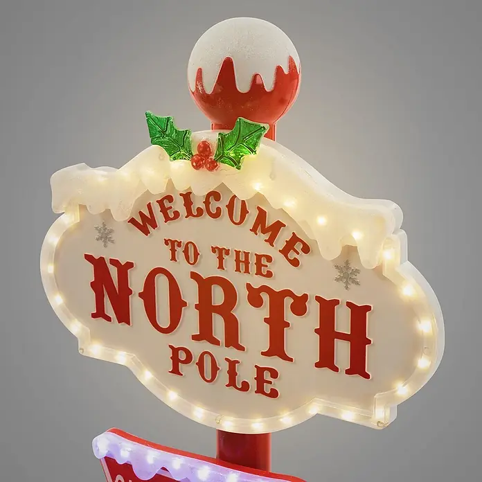 ECD Germany LED-Weihnachtsdekofigur LED Wegweiser Weihnachtsbeleuchtung Nordpol Schild Deko - Weiß, Rot, Grün, Netzbetrieben, LED - Beleuchtetes "Welcome to the North Pole" Schild mit roter Schrift, weißem Schneebesatz, grüner Stechpalme und rot-weißer Kugel oben.