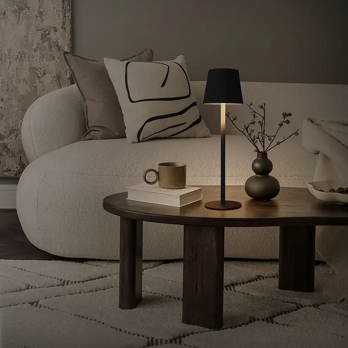 ML-Design LED-Tischleuchte rund Nachttischlampe Schwarz 4 Stufen Tragbare Metall LED Lampe - Schwarz, Schwarz - Eine beleuchtete schwarze Tischlampe mit plissiertem Schirm auf einem runden Holztisch neben einem Sofa im Wohnzimmer.