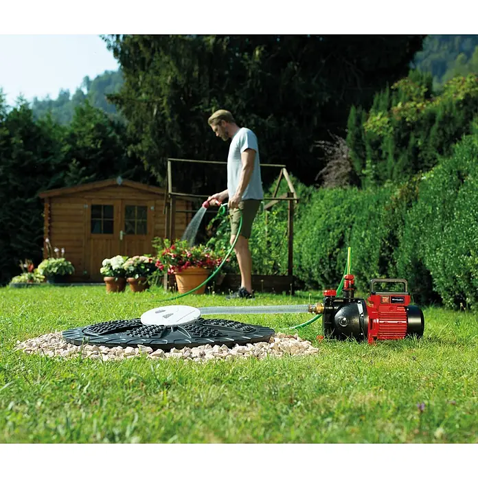 Einhell Gartenpumpe GC-GP 6040 ECO - Leistung: 600 W, Max. Fördermenge: 4.000 l/h - Rote und schwarze Gartenpumpe mit Schläuchen, an einen Bodenzugang angeschlossen, zur Bewässerung genutzt.