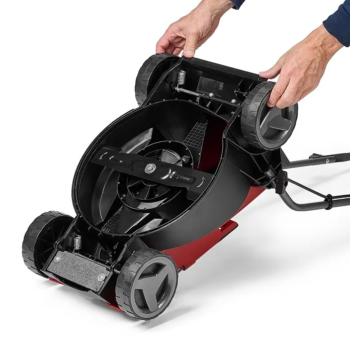 Einhell Power X-Change 18V Akku-Rasenmäher GE-CM 18/32 Li-Solo - 18 V, Ohne Akku, Schnittbreite: 32 cm - Hände halten die schwarz-rote Unterseite eines Rasenmähers mit Schneidmessern, Rädern und Höhenverstellung.