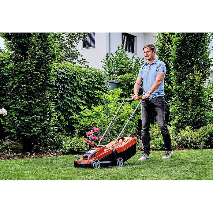 Einhell Power X-Change 18V Akku-Rasenmäher GE-CM 18/32 Li-Solo - 18 V, Ohne Akku, Schnittbreite: 32 cm - Ein Mann mäht grünes Gras mit einem orange-schwarzen Rasenmäher im Garten.