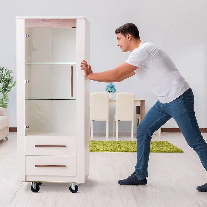ECD Germany Transportroller Transportroller mit Siebdruckplatte, Möbel-Transport Transporthilfe - Verbundwerkstoff - Weißer Vitrinenschrank mit Glastüren, Holzdetails und zwei Schubladen, ausgestattet mit Rollen für leichte Mobilität, beim Bewegen im Haus gezeigt.