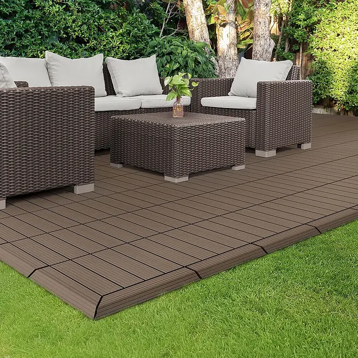 ML-Design Terrassenfliese Randabschlussleiste links Dunkelbraun 38x2x7,5 cm Eckleiste Umrandung - Dunkelbraun - Braune Rattan-Gartenmöbel mit weißen Kissen auf modularen braunen Terrassenfliesen im Garten.