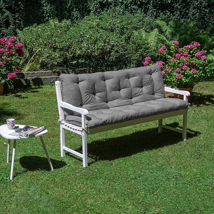 Beautissu Bankauflage Flair BR - Gartenbank, 1 Stk., L x B x H: 150 x 50 x 10 cm, Polyester, Hellgrau - Weiße Gartenbank mit grauen Polstern, ergänzt durch einen kleinen Beistelltisch im Freien.
