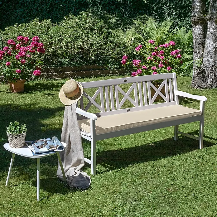 Beautissu Bankauflage Base BK - Gartenbank, 1 Stk., L x B x H: 180 x 48 x 5 cm, Polyester, Natur - Weiße Gartenbank mit beigem Kissen. Ein Strohhut und eine Decke liegen darauf, daneben ein Beistelltisch mit Pflanze und Zeitschrift.