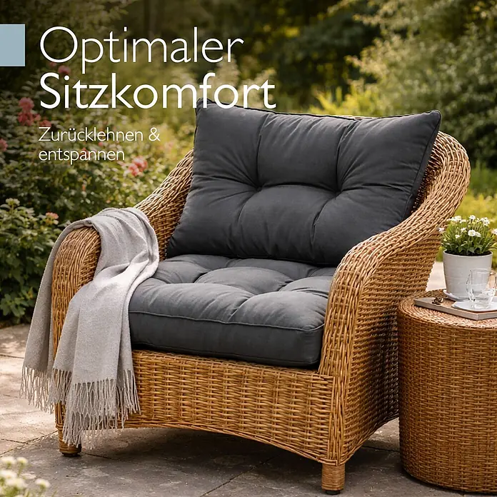 Beautissu Sitzauflage XLuna - Outdoor Lounge, 2 Stk., Polyester, Graphitgrau - Rattansessel mit dunkelgrauen Kissen und heller Decke auf einer Terrasse, daneben ein passender Beistelltisch. Bietet optimalen Sitzkomfort.
