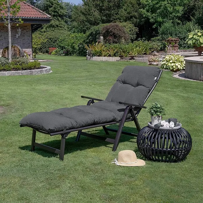 Beautissu Liegenauflage Flair RL - Rollliege, 2 Stk., Polyester, Graphitgrau - Dunkelgrauer gepolsterter Liegestuhl und Rattantisch in Gartenumgebung.