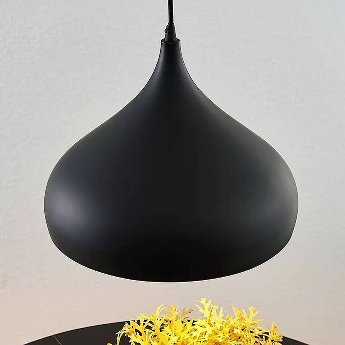 Lindby Pendelleuchte Ritana - schwarz, Schwarz, gold, E27 - Schwarze, tropfenförmige Hängeleuchte über einem Tisch mit einer gelben Zierpflanze.