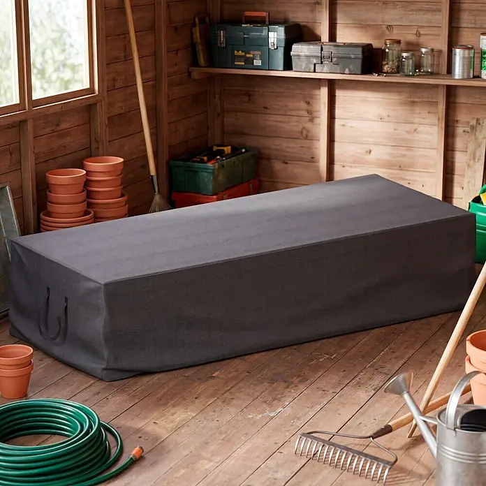 SENSUM Auflagen-Schutzhülle Tragetasche - L x B x H: 220 x 90 x 50 cm, Polyester, 140 g/m² - Dunkelgraue rechteckige Outdoor-Möbelabdeckung mit Griffen, in einem Holzschuppen mit Gartengeräten.