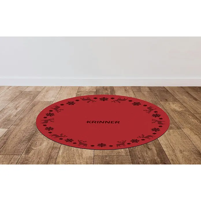 Krinner Dekoartikel - L x B x H: 60 x 60 x 0,7 cm, Rot - Rote runde Matte mit Rentier- und Schneeflockenmustern sowie dem Text 'KRINNER', auf einem Holzfußboden.