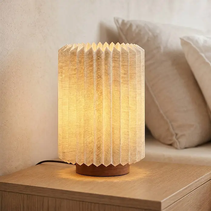 Lindby Tischleuchte Maveo - Holz dunkel, alu / grau / zink, E27 - Plissierte Stofftischlampe mit Holzsockel, warm leuchtend, auf einem Holztisch.