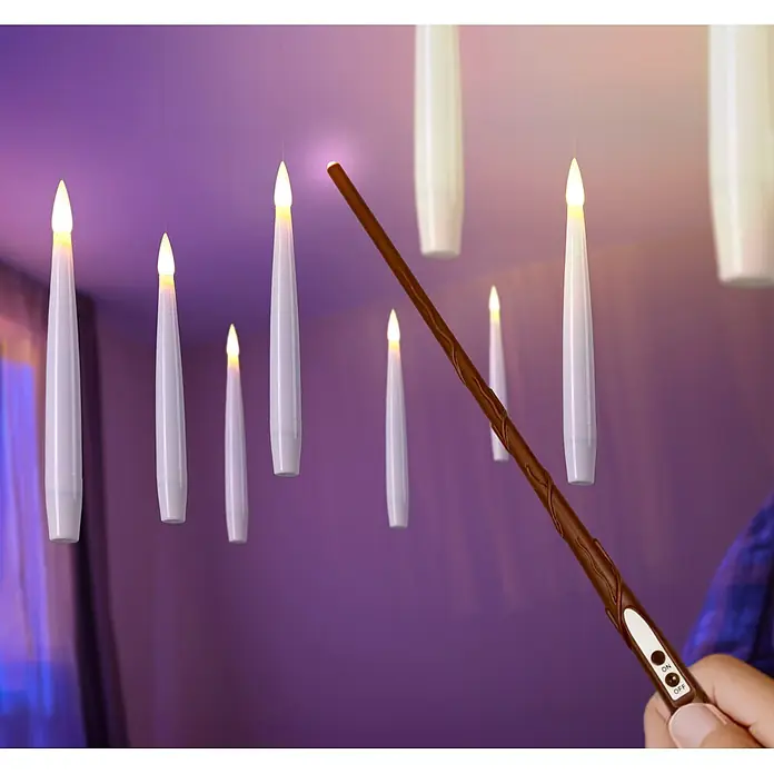 LED-Kerzen-Set Schwebend - Creme, 10 Stk., Warmweiß - Ein brauner Zauberstab mit Ein-/Ausschalter beleuchtet hängende weiße LED-Kerzen in einem lilafarbenen Raum.