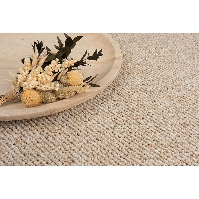 Bricoflor Teppichboden Meterware 2x4m, Schlinge Berber, beige hell-braun - Schlinge, 100 % Polypropylen (PP), beige hell-braun - Nahaufnahme eines naturbeigen strukturierten Teppichs mit einem Holztablett und einem Trockenblumenstrauß als Dekoration.