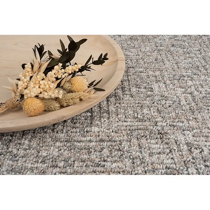 Bricoflor Teppichboden Meterware 2,5x5m, Schlinge gemustert, hell-grau - Schlinge, 100 % Polypropylen (PP), hell-grau - Strukturierter Melange-Schlingenflor-Teppich in Grau, Weiß und Beige, mit Trockenblumenarrangement auf einem Holztablett.