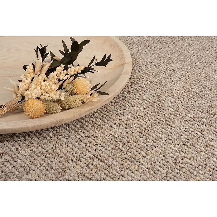 Bricoflor Teppichboden Meterware 3x4m, Schlinge Berber, beige braun - Schlinge, 100 % Polypropylen (PP), beige braun - Ein Strauß getrockneter cremefarbener, beiger und dunkelgrüner Blumen, mit Schnur gebunden, auf einem hellen Holztablett auf einem beigen Teppich.