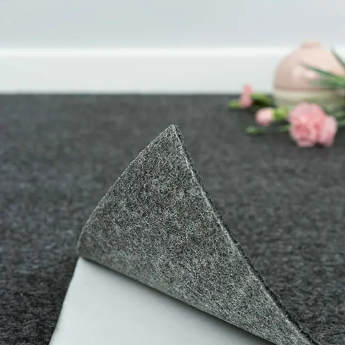 Bricoflor Teppichfliese Nadelvlies Nadelfilz, Schwarz Anthrazit, 40x40cm -  - Dunkelgraues selbstklebendes Filzmaterial wird abgezogen, um die weiße Rückseite zu zeigen.