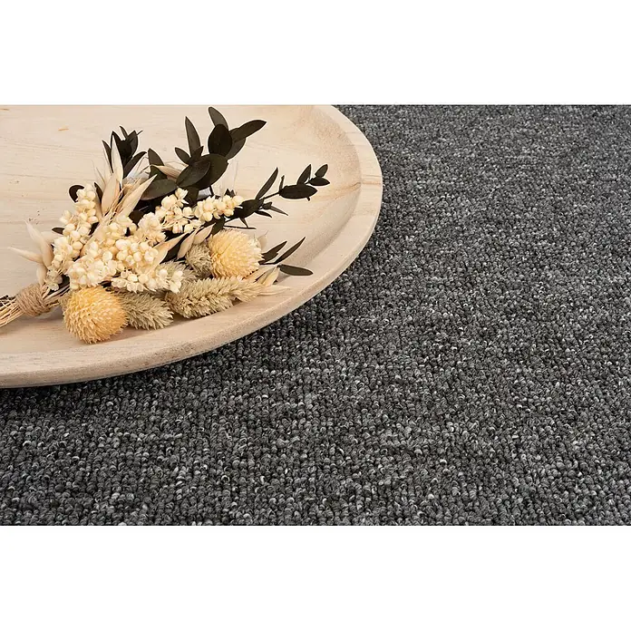 Bricoflor Teppichboden Meterware 8x4m, Schlinge gemustert, dunkel-grau anthrazit - Schlinge, 100 % Polypropylen (PP), dunkel-grau anthrazit - Kleiner Strauß getrockneter, heller Blumen und dunklem Laub, mit Schnur gebunden, auf einer runden Holzschale, auf einem gesprenkelten grauen Teppich.