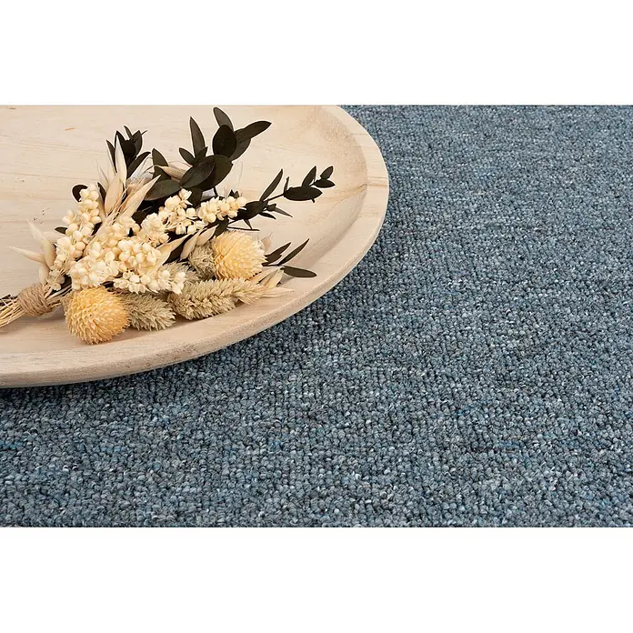 Bricoflor Teppichboden Meterware 2x5m, Schlinge gemustert, blau grau - Schlinge, 100 % Polypropylen (PP), blau grau - Ein kleiner Strauß getrockneter Blumen in Beige und Hellgelb mit dunklen Blättern auf einem hellen Holztablett, auf einem blauen Teppich.
