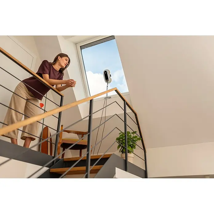 Kärcher Fensterreinigungsroboter RCW 2 - Wassertankvolumen Roboter: 70 ml, Saugkraft: 3.300 Pa - Ein weiß-gelber Fensterputzroboter reinigt ein Dachfenster.