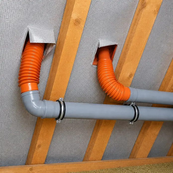 Sarei HT-Flexschlauch - Durchmesser: 70 mm - 100 mm, Länge: 500 mm, PVC - Orangefarbene flexible und graue starre Lüftungsrohre in einem Dachboden mit reflektierender Isolierung und Holzbalken installiert.