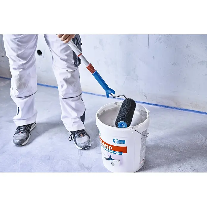 Knauf Spachtelwalze - 240 mm - Eine Person taucht eine schwarze Farbrolle an einer Teleskopstange in einen weißen Eimer Spachtelmasse.