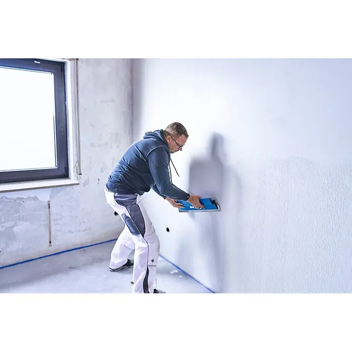 Knauf Glätt- & Flächenspachtel - 600 mm, Edelstahl - Mann glättet eine Wand mit einer blauen Verputzkelle.