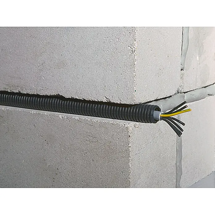 Flexrohr EN20 betonfest - Beton, 100 m, Kunststoff, 750 N, Schwarz, 20 mm - Flexibles, schwarzes Installationsrohr mit Kabeln, die aus der Öffnung ragen, eingebettet in eine Betonsteinwand.
