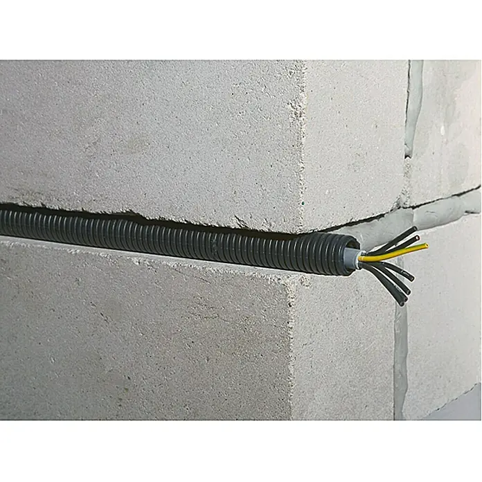 Flexrohr EN20 betonfest - Beton, 100 m, Kunststoff, 750 N, Schwarz, 20 mm - Flexibles, schwarzes Installationsrohr mit Kabeln, die aus der Öffnung ragen, eingebettet in eine Betonsteinwand.