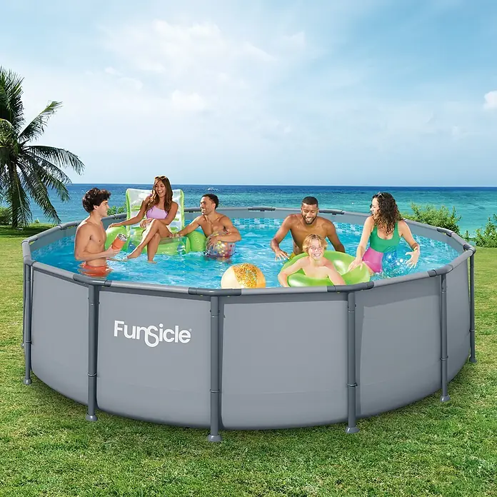 Funsicle Frame-Pool - Ø x H: 427 x 107 cm, Grau, 13.294 l - Grauer Funsicle Aufstellpool mit Personen beim Schwimmen und Entspannen, auf Rasen vor tropischem Meer und Palmenhintergrund.