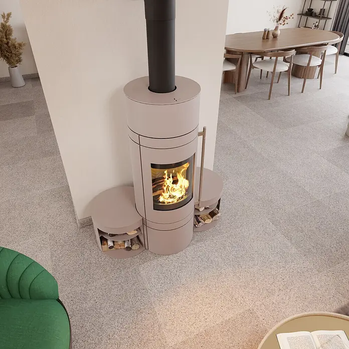 Kaminofen - 5,5 kW, Stahl, Magnolia - Rosafarbener freistehender Kaminofen mit integrierter Holzlagerung und brennendem Feuer in einem modernen Wohnraum.