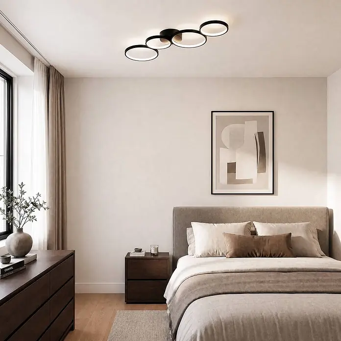 Lindby Deckenleuchte Evengeline - schwarz - Schwarze moderne LED-Deckenleuchte mit ineinandergreifenden Ringen, die ein Schlafzimmer beleuchtet.