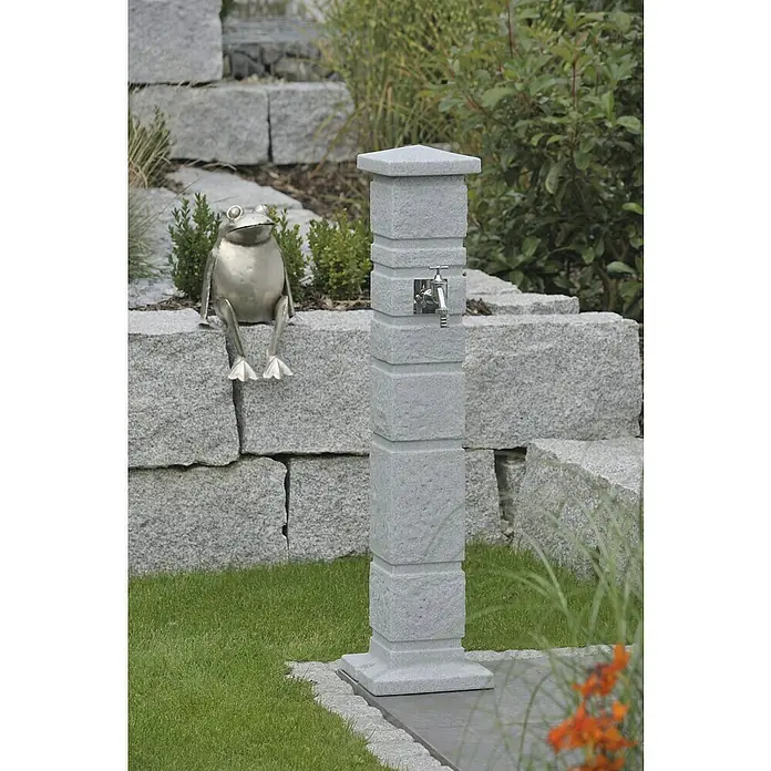 Arves Wasserzapfstelle Romana - Granitfarben, Höhe: 110 cm, Ausstattung: Wasserhahn - Detailaufnahme eines stilvollen Wasserhahns aus grauem Stein im Garten, mit einer dekorativen Froschfigur auf einer Steinmauer.
