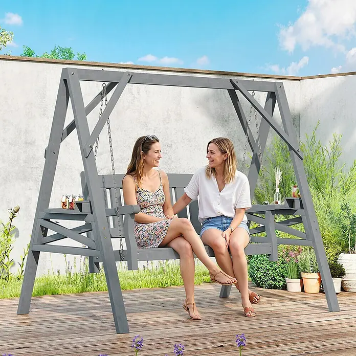 Outsunny Hängebank - B x T x H: 120 x 120 x 160 cm, Tannenholz, Metall, Grau - Graue Holz-Gartenschaukel mit A-Rahmen, auf der zwei Frauen die Natur genießen. Mit integrierten Beistelltischen.